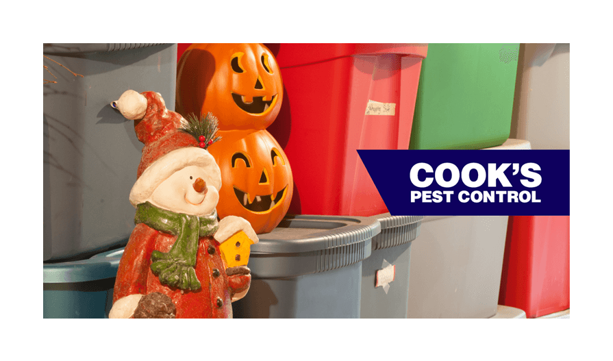 Several plastic tubs of holiday decorations with Cook's Pest Control Logo.