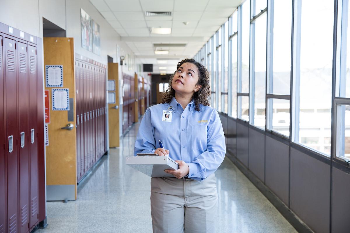 A Cook's Pest Control employee inspecting a school hallway.