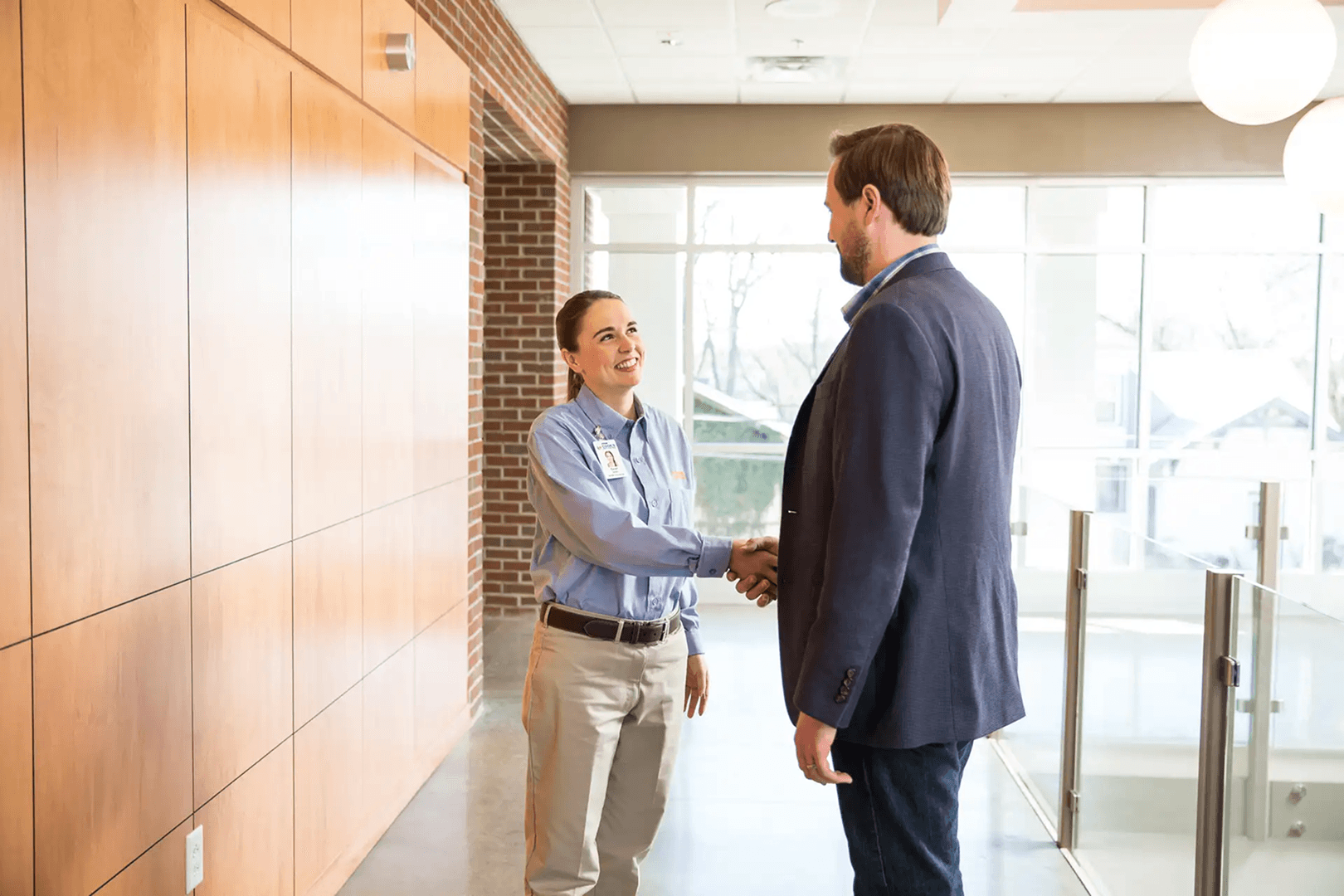 Commercial pest control representative shaking hands with a business manager inside a professional office building.